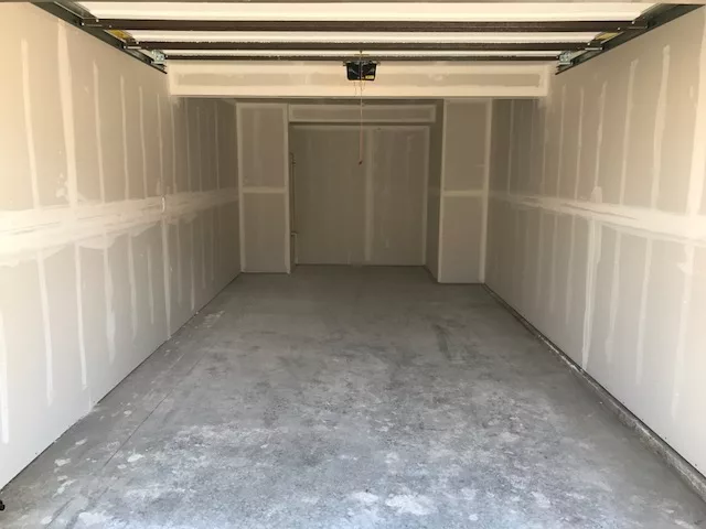 Empty garage with unfinished drywall and a concrete floor.